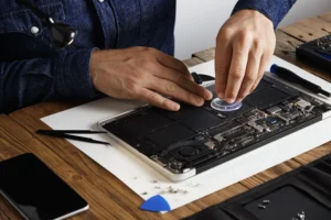 master-uses-small-suction-cup-change-battery cells from broken laptop repair clean it his laboratory with specific toolkit wooden table around